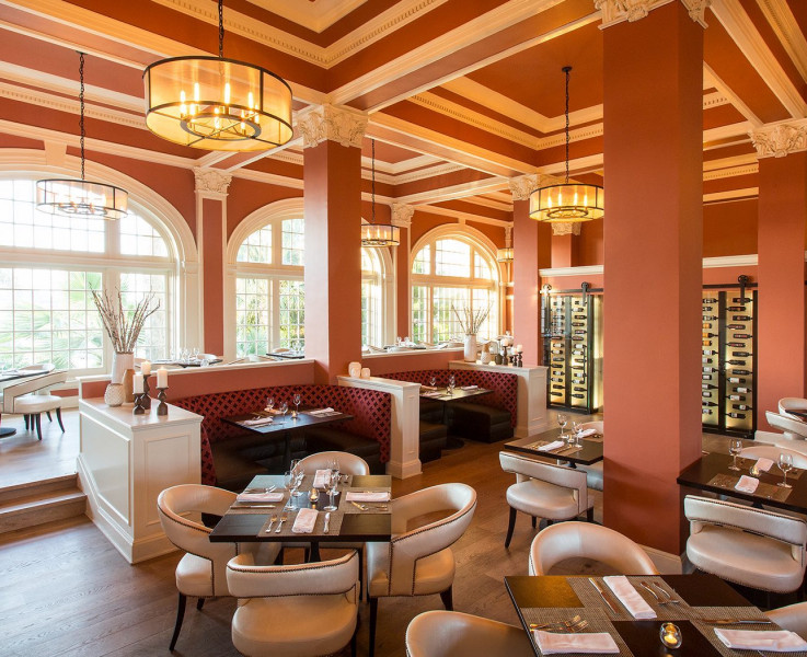 An elegant dining area with booth and table seating and a wine cellar in the back
