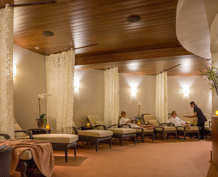 The spa area with cushioned lounge chairs divided individually by white curtains