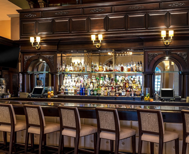 Empty bar area with dark wood features and plenty of barstool seating