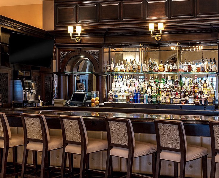 softly lit dark wooden bar with glass shelves and bottles