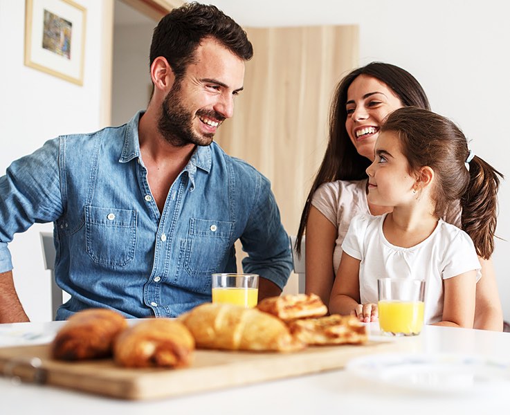 happy family eating breakfast together at a table with croissants and juice