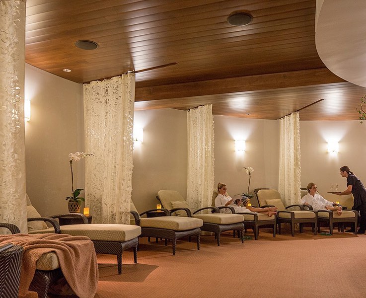 spa interior with chaise lounges and guests being served drinks by staff